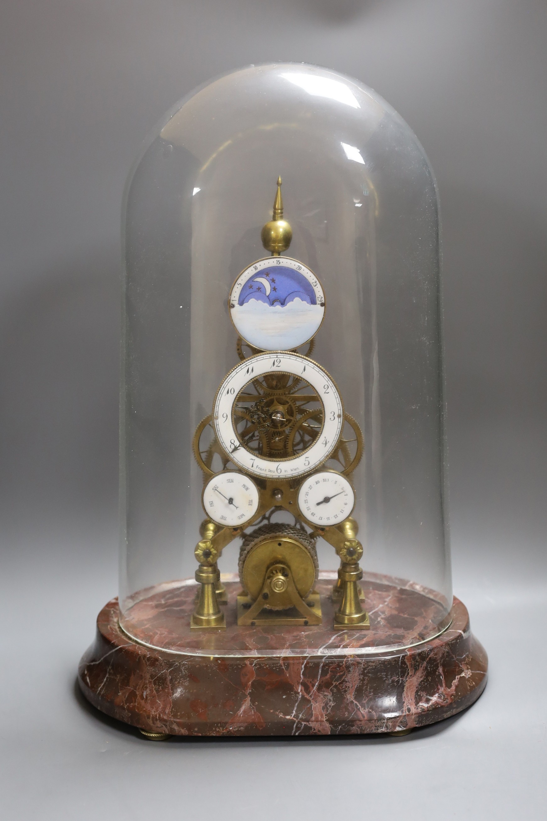 A calendar skeleton clock with moon phase dial, pin wheel escapement, dial signed Franz Denk in Wien, with pendulum, 50cm tall including dome